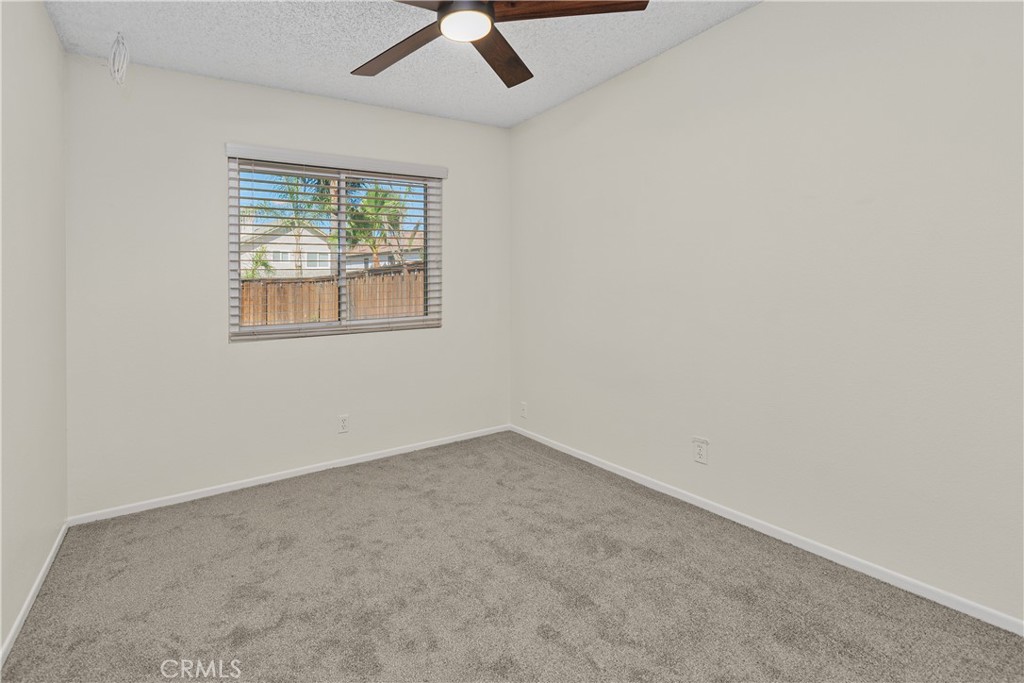 Another comfortable secondary bedroom featuring carpeted flooring, a ceiling fan, and natural light, with flexibility for guests, hobbies, or a home office.