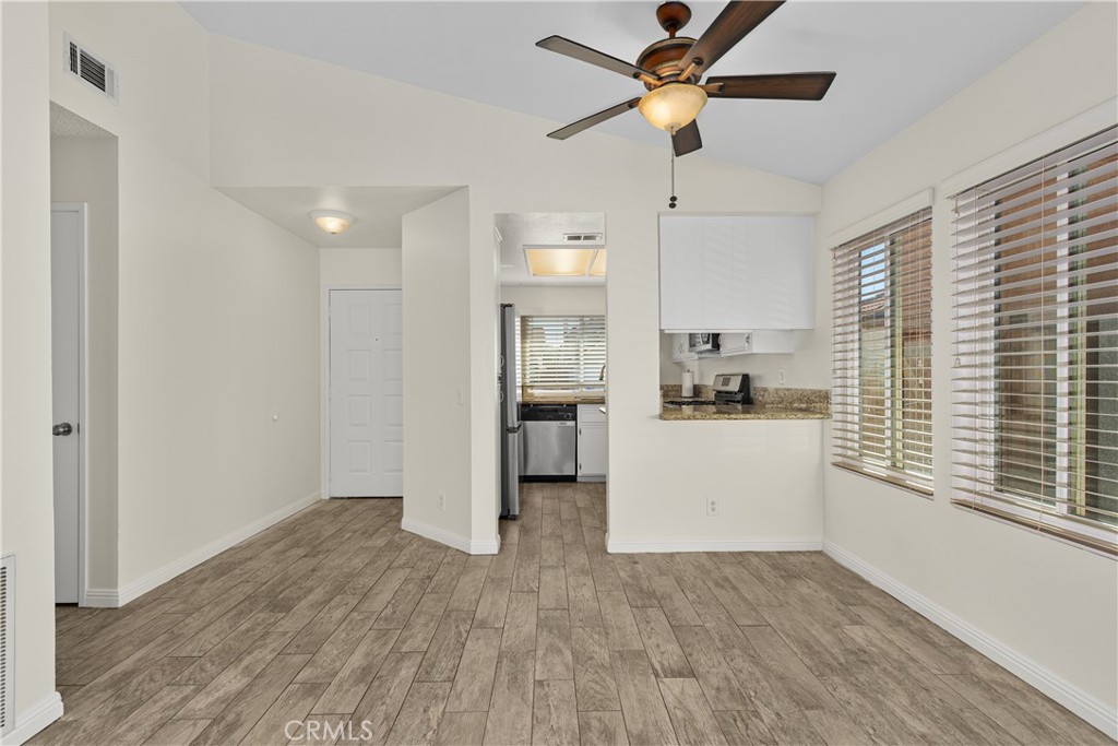 Dining area conveniently situated beside the kitchen, featuring a ceiling fan, large windows, and an open connection to the living space.