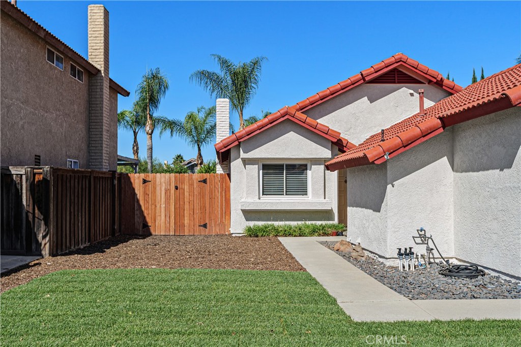 Side view of the home showcasing the maintained lawn, concrete walkway, and gated yard access. Side view of the home showcasing the maintained lawn, concrete walkway, and gated yard access.