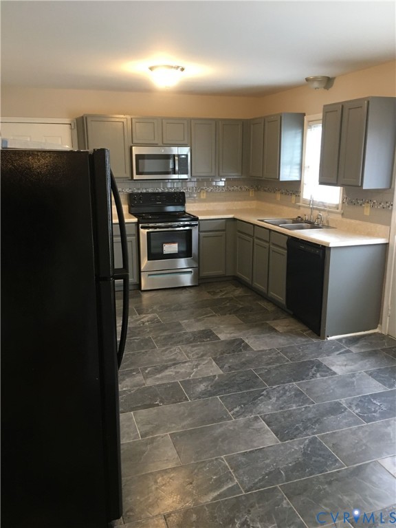 Kitchen featuring gray cabinets, black appliances, light countertops, and backsplash Kitchen featuring gray cabinets, black appliances, light countertops, and backsplash