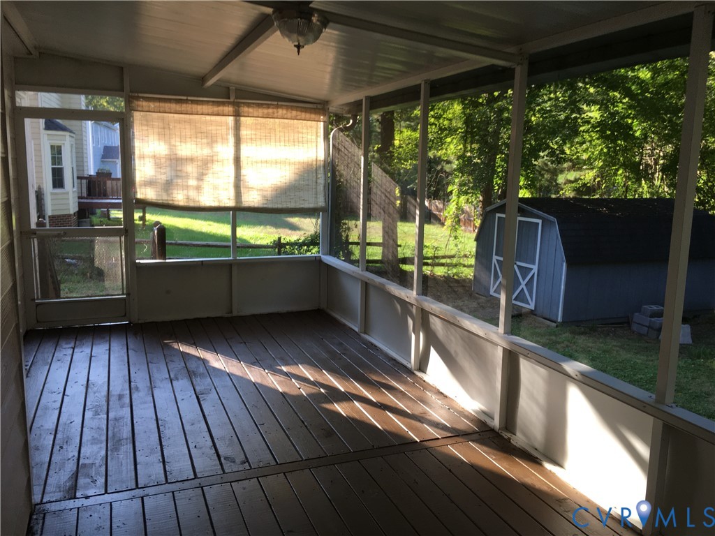 Unfurnished sunroom featuring vaulted ceiling and a wooden deck