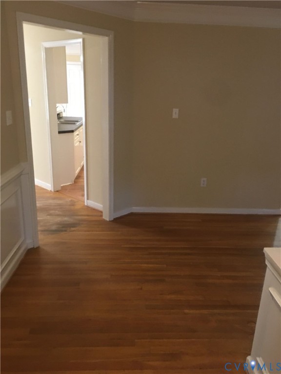 Spare room featuring dark wood finished floors and crown molding