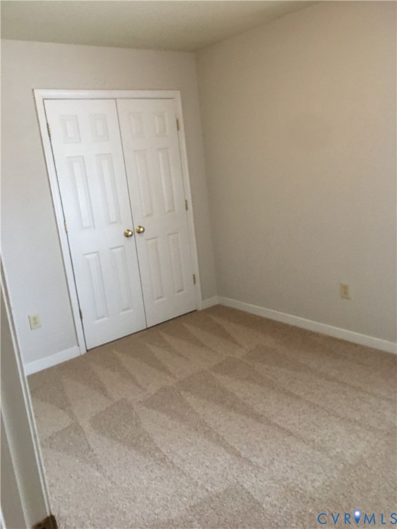 Unfurnished bedroom with light colored carpet and a closet