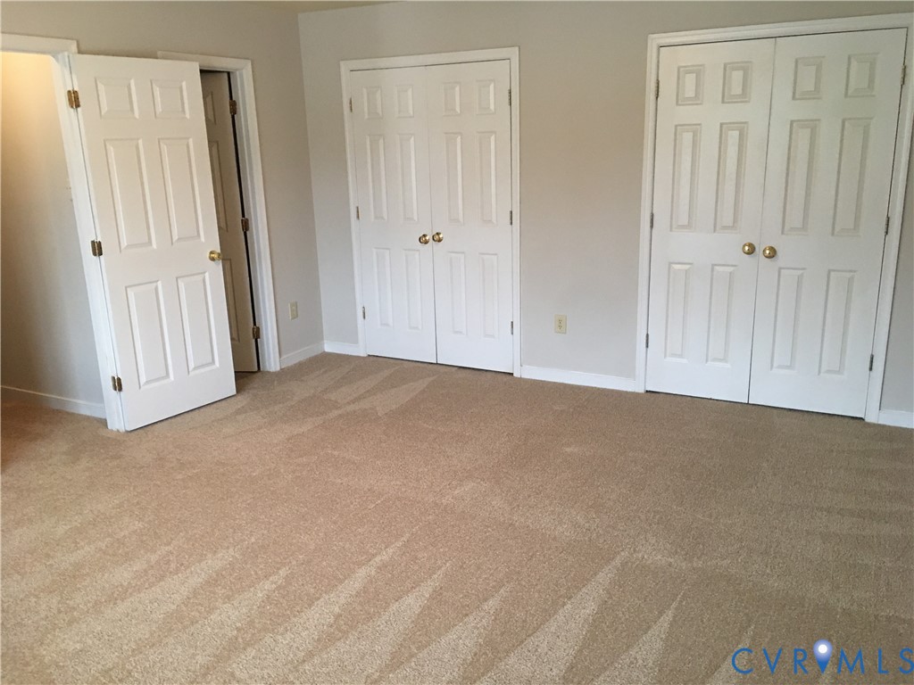 Unfurnished bedroom with light carpet and multiple closets