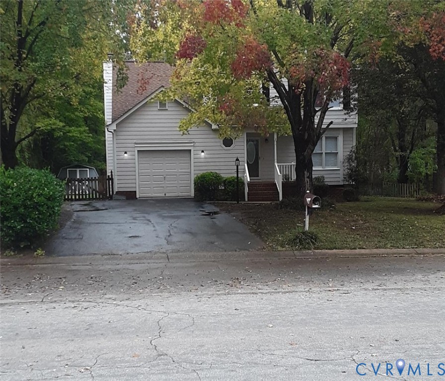 View of property hidden behind natural elements with driveway, an attached garage, and a chimney View of property hidden behind natural elements with driveway, an attached garage, and a chimney