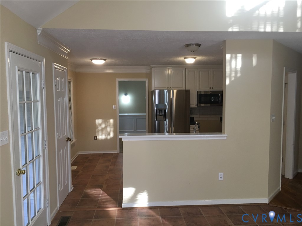 Kitchen featuring stainless steel appliances, dark tile patterned floors, light countertops, backsplash, and crown molding