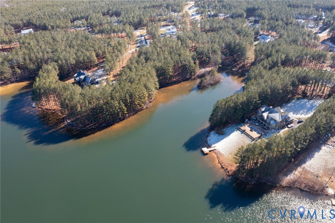 Aerial view of property's location featuring a large body of water and a forest