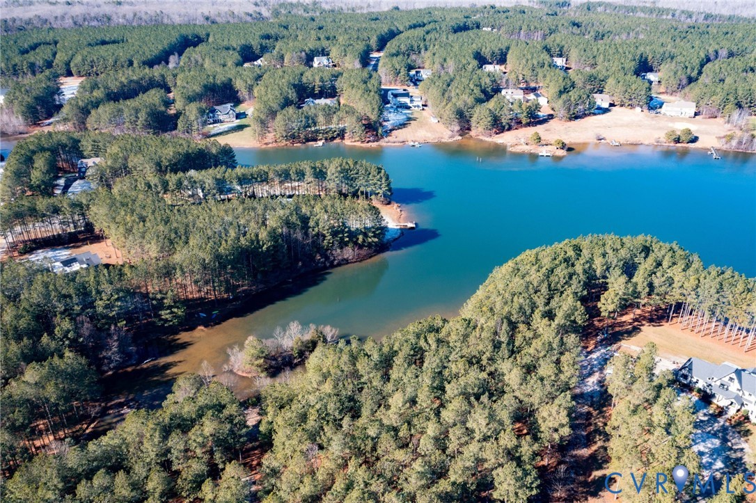 Aerial overview of property's location featuring a forest and a large body of water