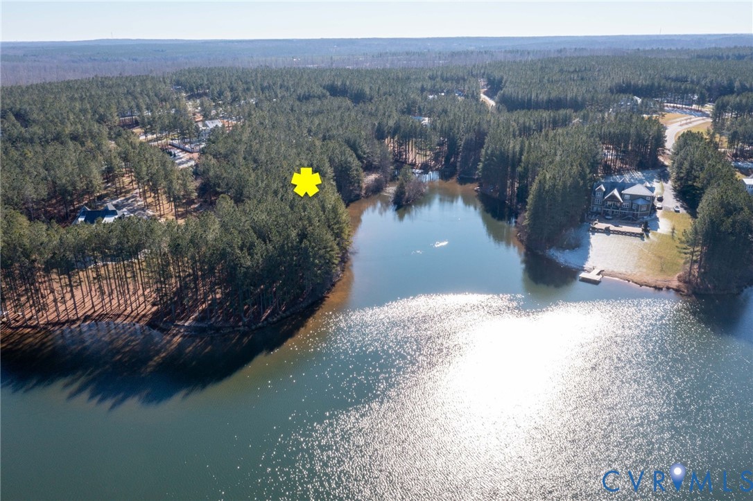 Aerial view of property and surrounding area featuring a heavily wooded area and a nearby body of water