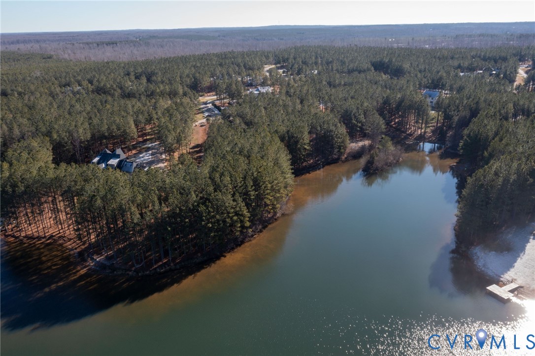 Aerial view of property and surrounding area featuring a heavily wooded area and a large body of water