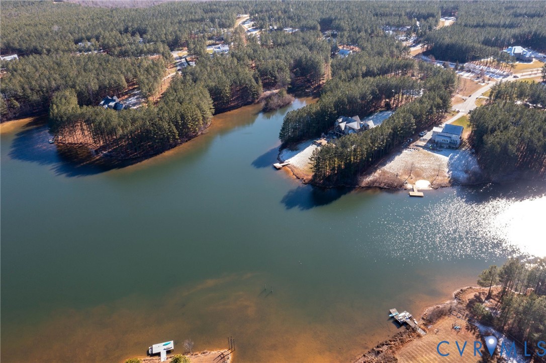 Drone / aerial view of a nearby body of water and a heavily wooded area