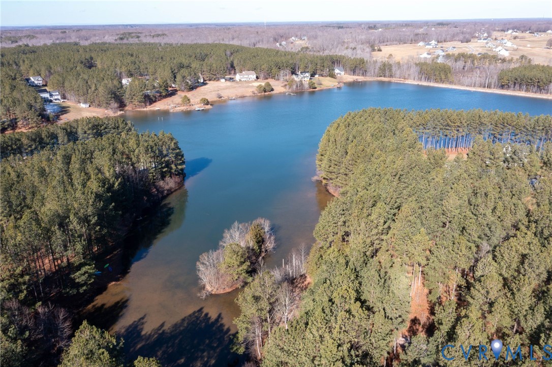Aerial overview of property's location with a nearby body of water and a heavily wooded area