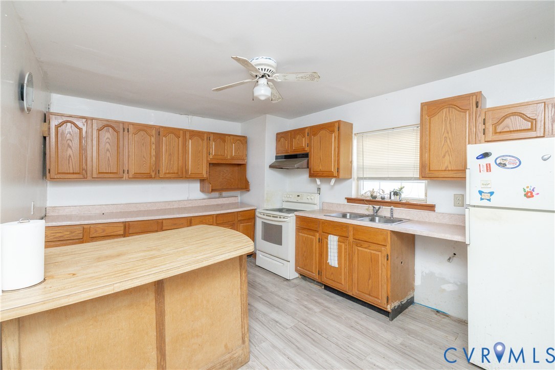Kitchen featuring white appliances, a ceiling fan, light wood-type flooring, wood counters, and wood finish cabinets Kitchen featuring white appliances, a ceiling fan, light wood-type flooring, wood counters, and wood finish cabinets