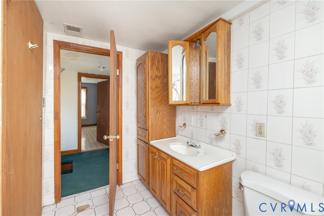 Half bath featuring tile walls, vanity, and light tile patterned flooring