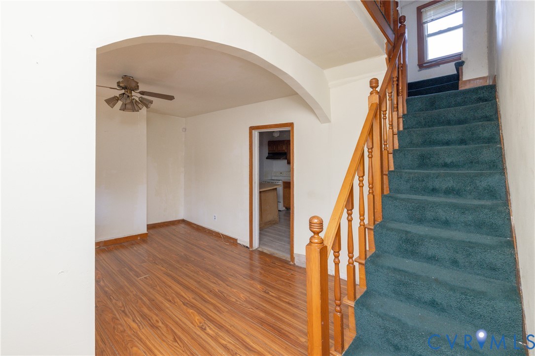 Stairs featuring arched walkways, wood finished floors, and a ceiling fan Stairs featuring arched walkways, wood finished floors, and a ceiling fan