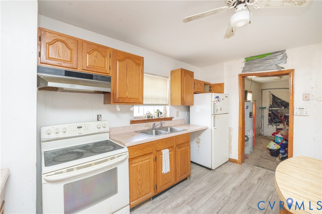 Kitchen with white appliances, light countertops, a ceiling fan, light wood-style floors, and wood finish cabinets