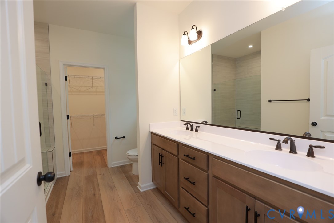 The photo represents the plan, not the actual home. Design selections may vary.  The first-floor primary suite offers a spacious walk-in closet and an ensuite bath with a double vanity, soaking tub, and linen closet.