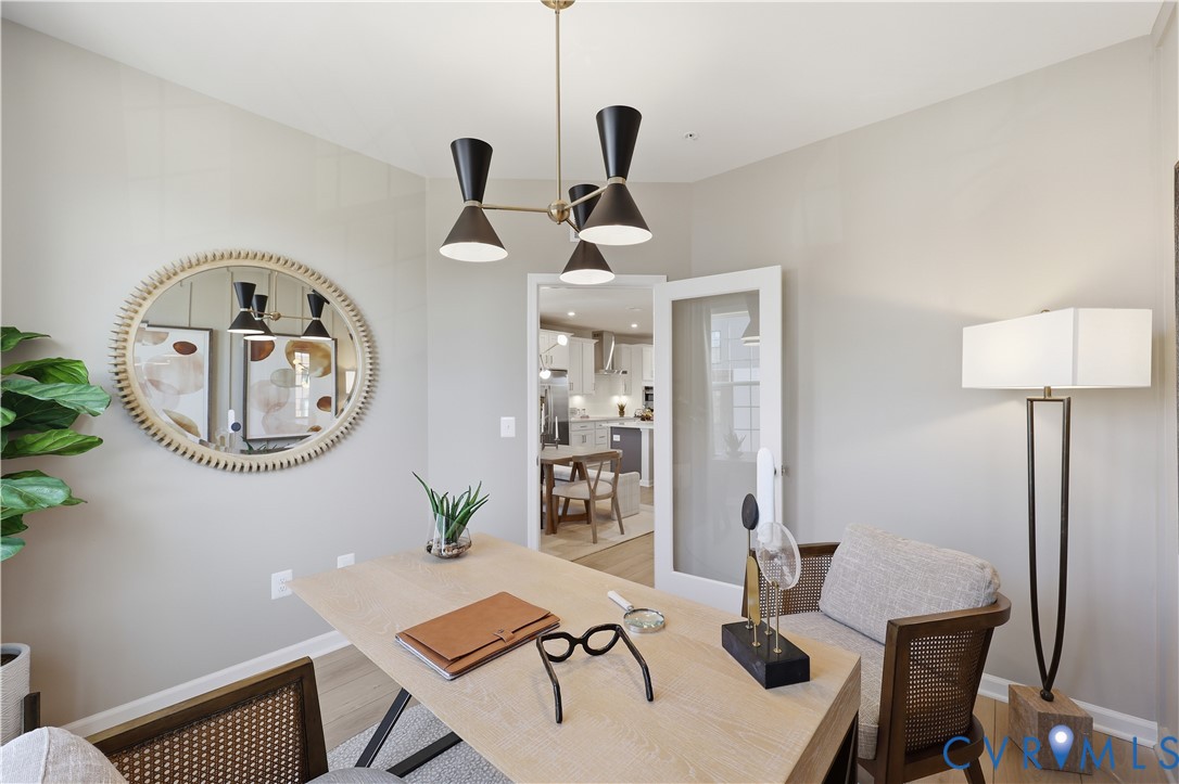 Dedicated room featuring light wood-finish flooring, a contemporary chandelier, a white framed glass-panel door, and smooth painted walls