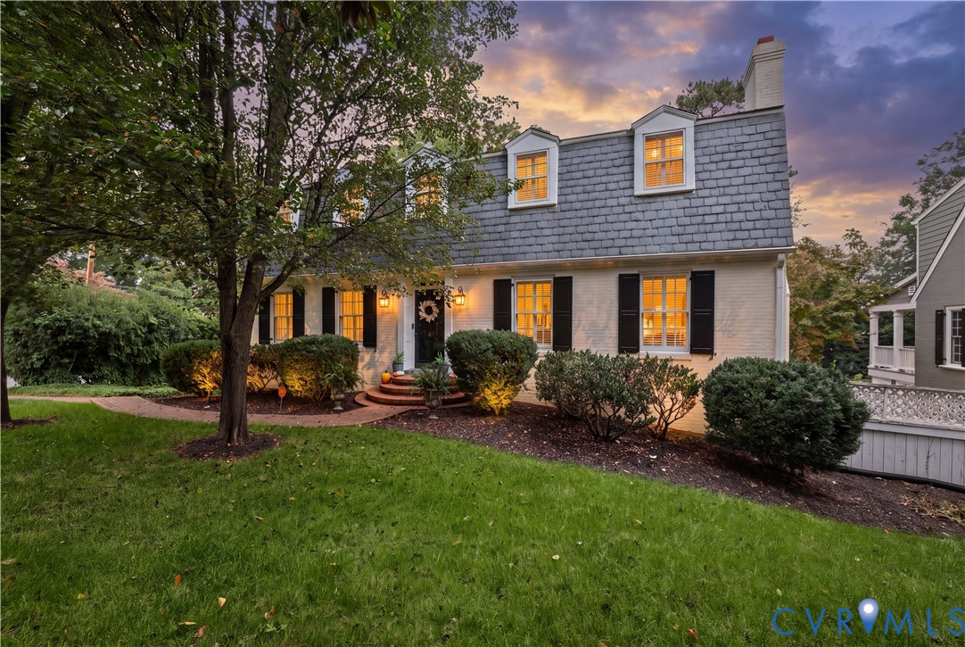 Dutch Colonial exterior featuring a gambrel roof, dormer windows, brick facade, and dark shutters