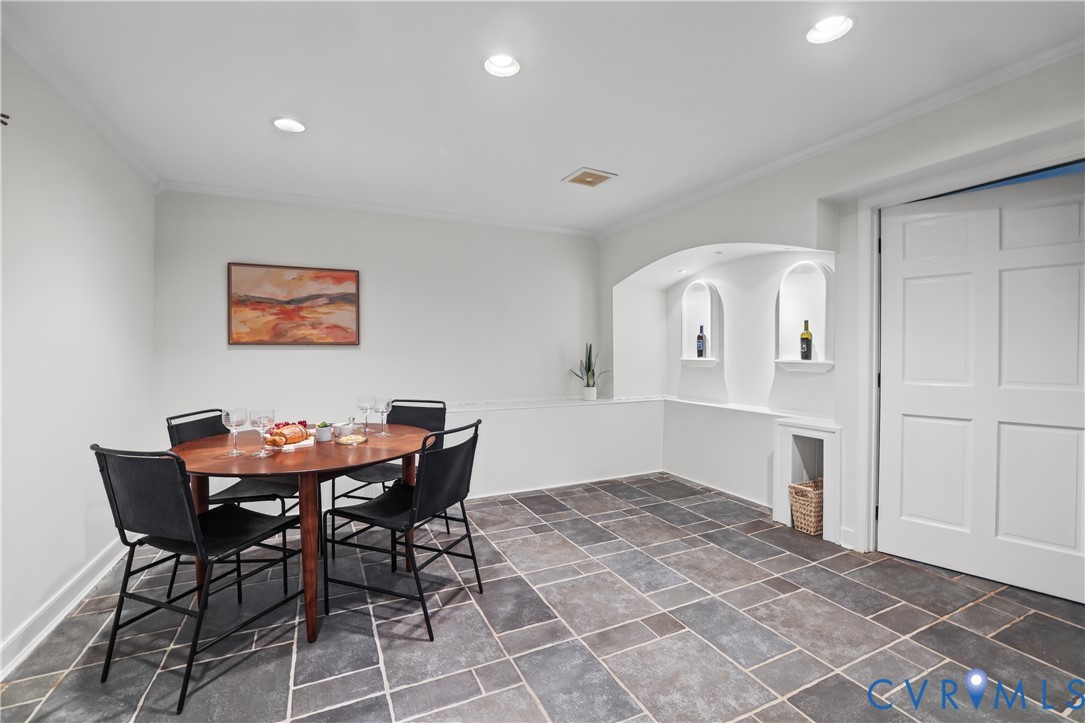Multi-tone stone tile flooring, recessed ceiling lighting, and arched wall niches with built-in shelving