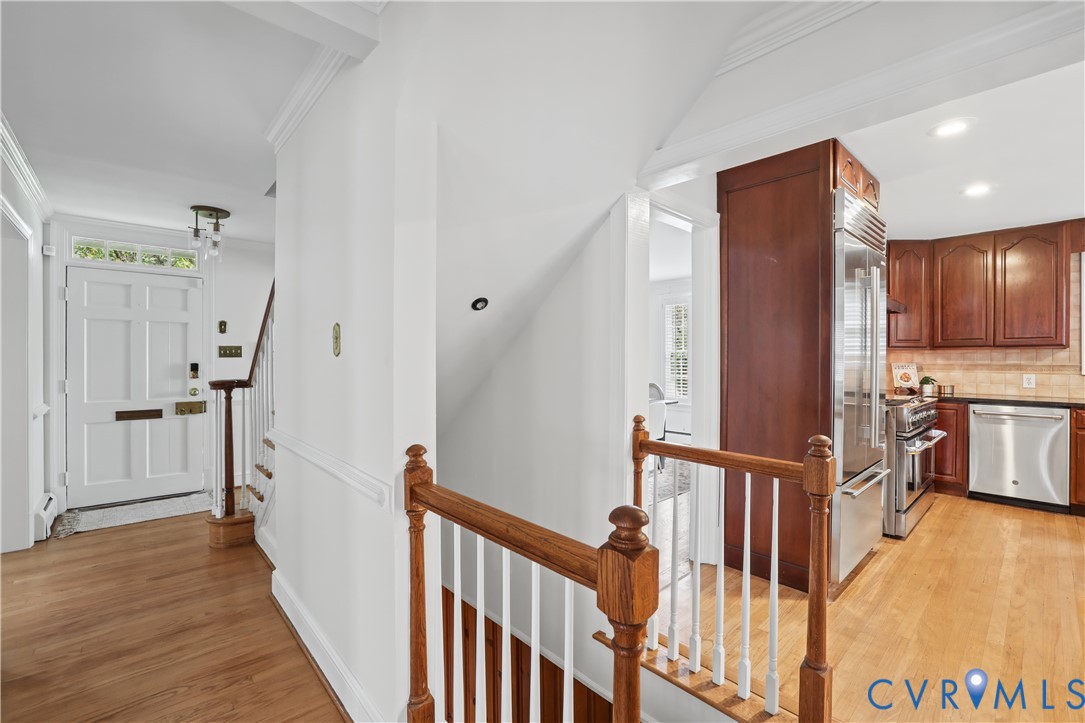 Entryway featuring a multi-panel door with transom window, wood-finish flooring, and a decorative wood banister