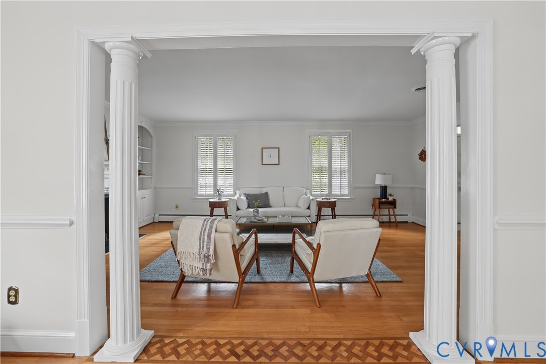 Architectural entryway featuring fluted columns, hardwood flooring with decorative inlay detail, and built-in shelving
