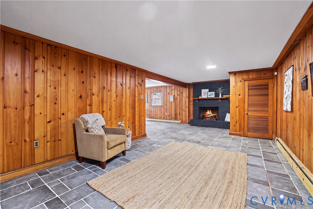 Basement Rec Rm featuring wood paneling, slate tile flooring, a painted brick fireplace with a mantel, and a louvered wooden door