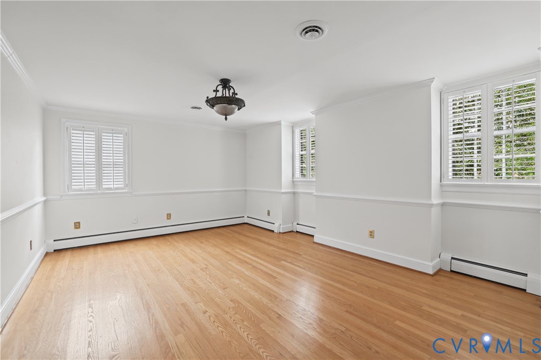 Interior space featuring wood-finish flooring, chair rail molding, shutter-style window coverings, and a central multi-arm ceiling light fixture