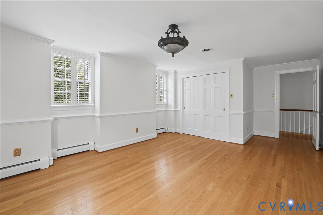 Wood-finish flooring, multi-panel doors, chair rail molding, shutter-style window treatments, and a decorative ceiling light fixture