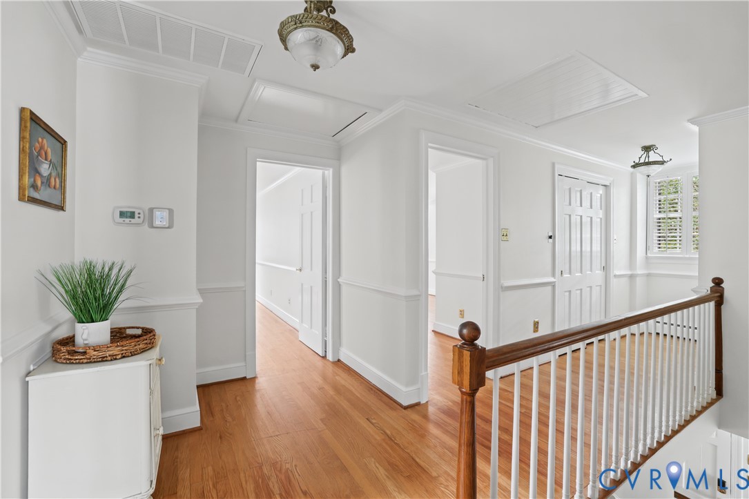 Interior hallway featuring wood-finish flooring, chair rail molding, solid-panel doors, and a wood-and-spindle stair railing