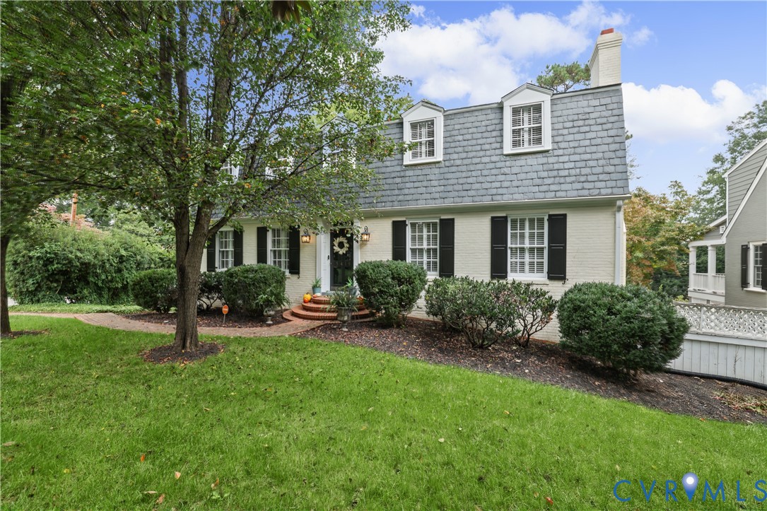 Dutch Colonial exterior featuring a painted brick facade, slate-shingle mansard roof, dormer windows, and a brick-stepped entryway Dutch Colonial exterior featuring a painted brick facade, slate-shingle mansard roof, dormer windows, and a brick-stepped entryway