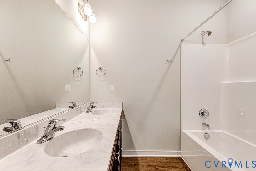 Dual vanity with integrated sinks, white marble-look countertop, chrome fixtures, and a frameless mirror