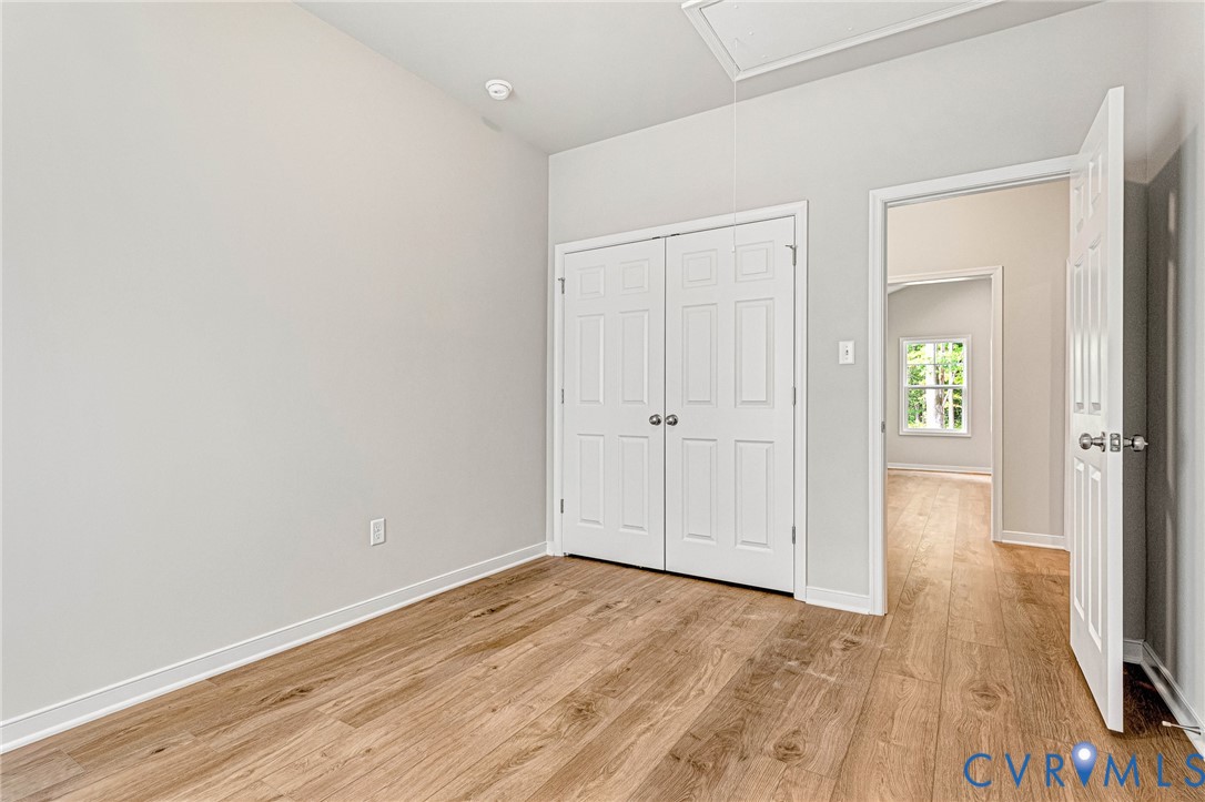 Room featuring wood-finish flooring, light grey walls, and white trim