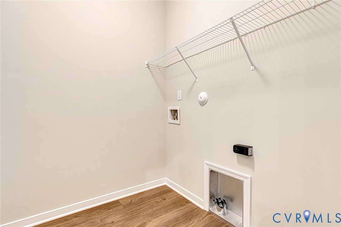 Utility space featuring wood-finish flooring, light-toned walls, and white baseboards