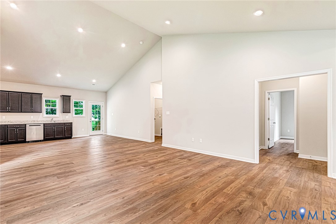 Spacious living area featuring wood-finish flooring and a high vaulted ceiling with recessed lighting