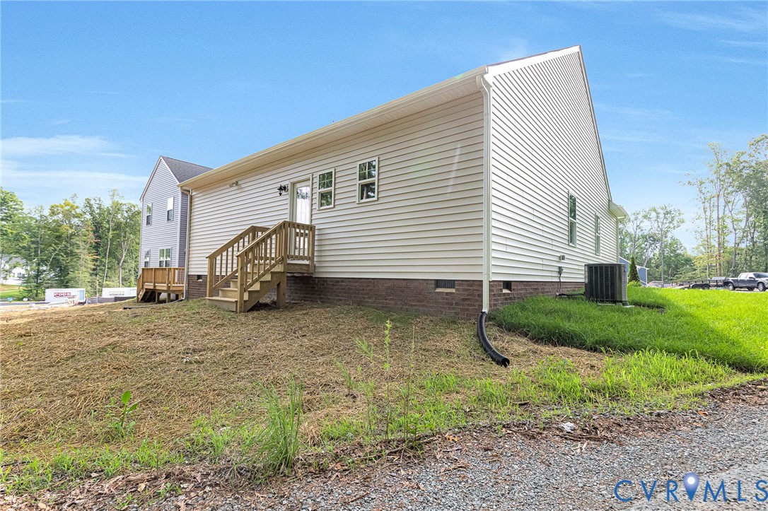 Rear exterior featuring horizontal siding, a wooden deck with stairs, a brick foundation, and an exterior HVAC unit