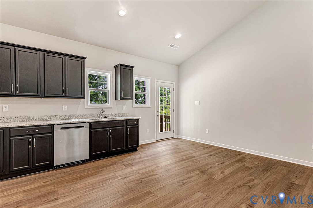 Kitchen area featuring dark cabinetry, speckled countertops, and stainless steel dishwasher