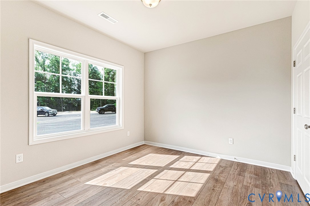Bright room featuring wood-finish flooring, a large window with white trim, and light neutral walls
