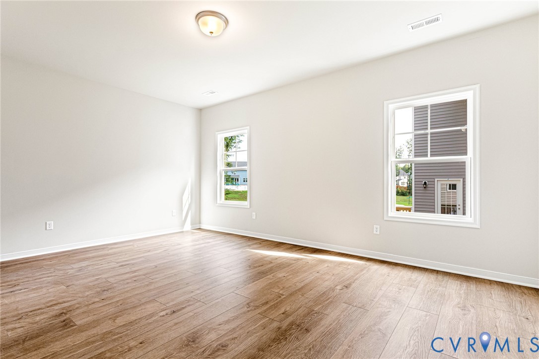 Bright room featuring wood-finish flooring, white walls, and two double-hung windows