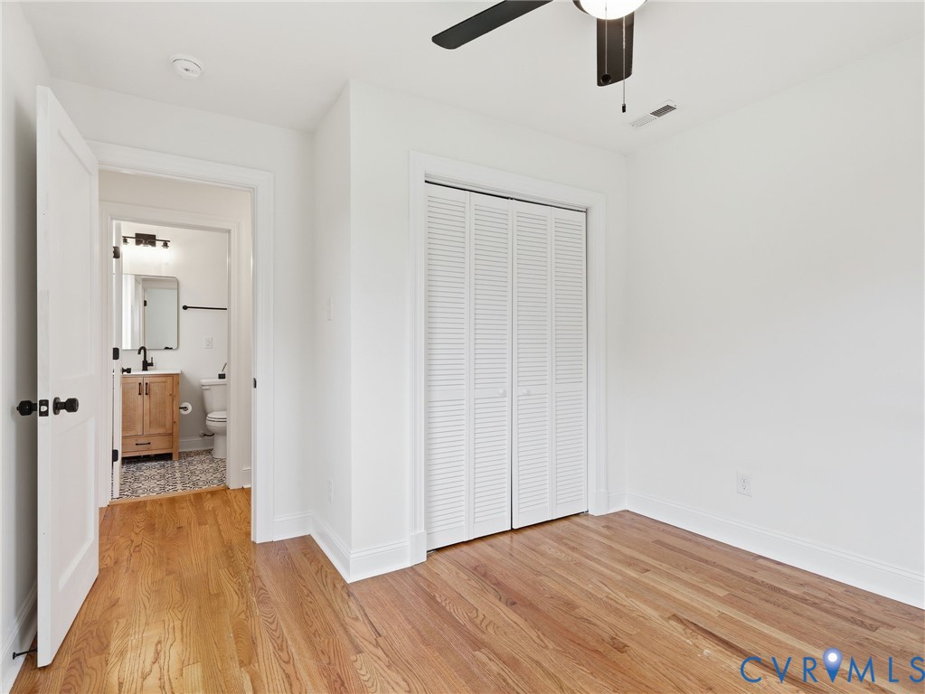 Room featuring wood-finish flooring, crisp white walls, and a ceiling fan with integrated lighting
