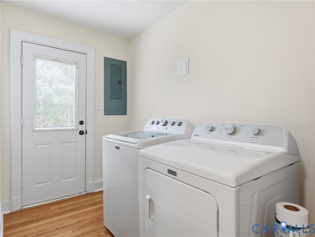 Laundry area featuring a wood-finish floor, light-colored walls, and a white exterior door with a window