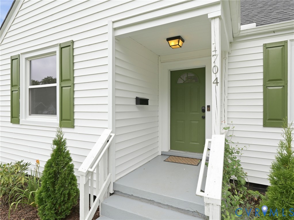 Entry features a green paneled door with an arched window, complemented by white siding and matching green shutters