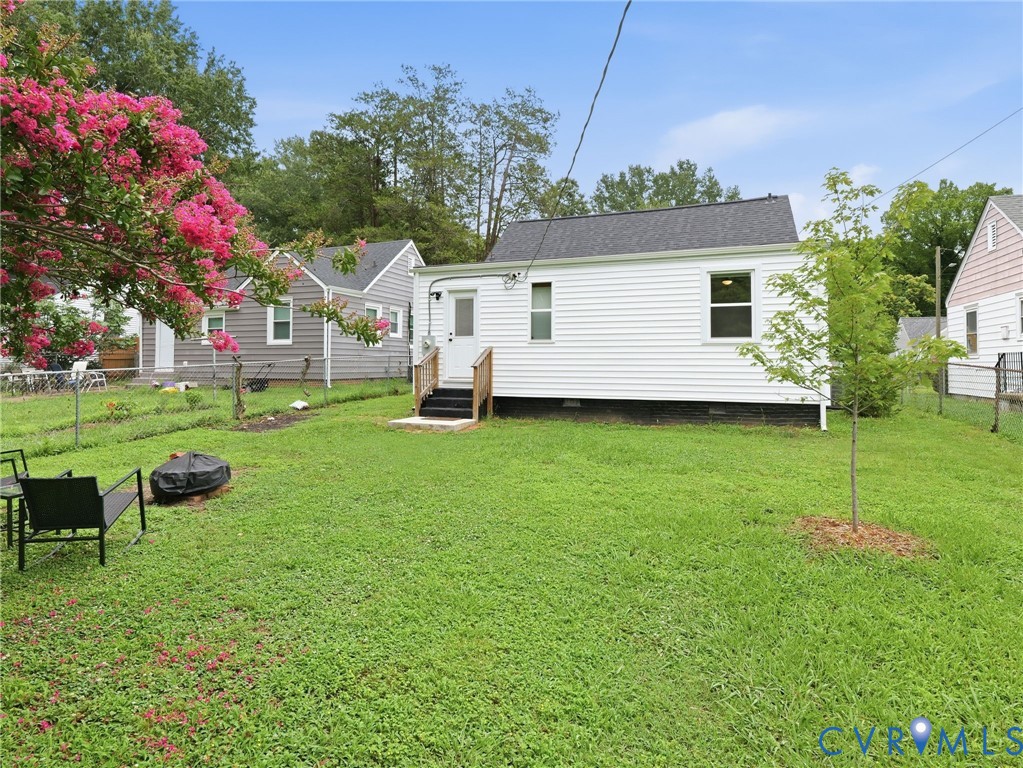 Expansive backyard featuring a manicured lawn, a flowering tree, and a rear exterior with white siding