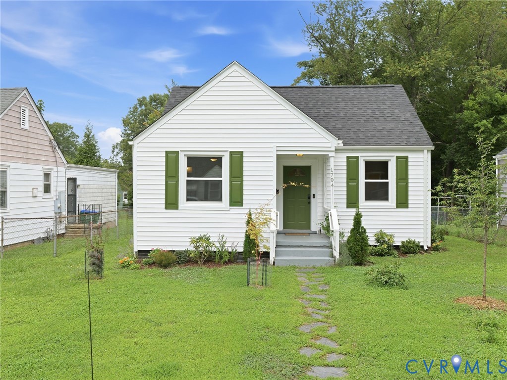 White siding exterior with a dark shingle roof and a green front door
