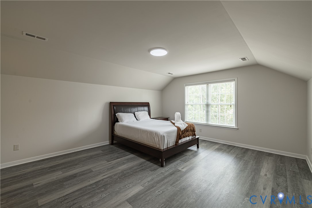 Room featuring wood-finish flooring, a vaulted ceiling, recessed lighting, and a window with blinds