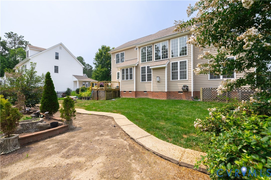 Rear exterior featuring a large expanse of green lawn, multiple windows across two levels, and a concrete pathway