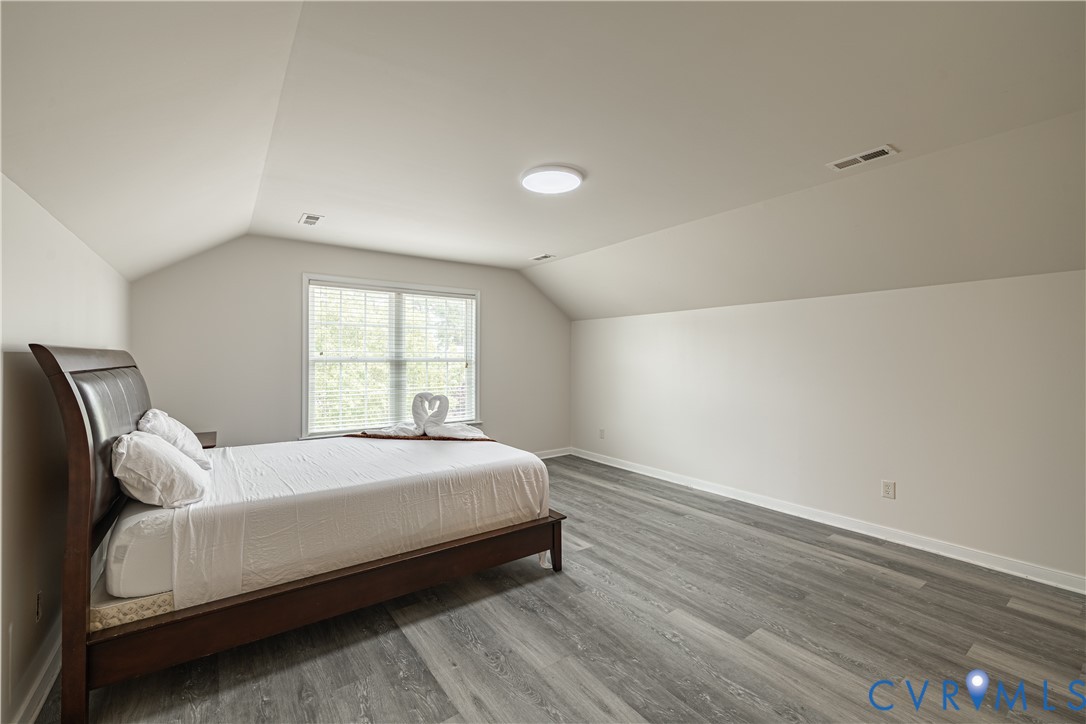 Bright room featuring hardwood flooring, white walls, two double-hung windows with blinds, and white crown molding