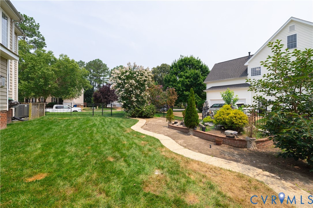 Expansive outdoor space featuring a manicured lawn, a paved pathway, and established landscaping