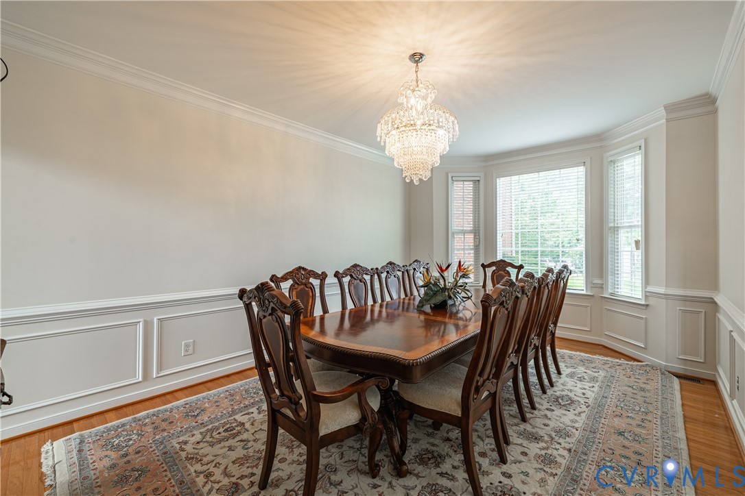Formal dining space featuring a tiered crystal chandelier and hardwood flooring
