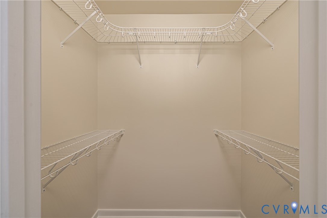 Walk-in closet featuring light beige walls, white baseboards, and a comprehensive white wire shelving system